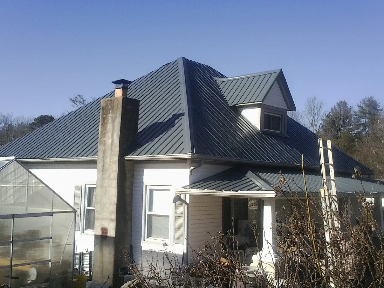 Dark blue standing seam metal roof on a white farmhouse with dormer — Slate & Tile Roof Repair by Roofing Brothers in Clarkton