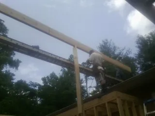 Carpenter setting a ridge beam over a new addition frame — Ice Dam Removal by Roofing Brothers in Clarkton