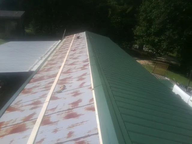 Old rusted panels beside newly installed green metal roofing — Wind Damage Roof Repair by Roofing Brothers in Clarkton