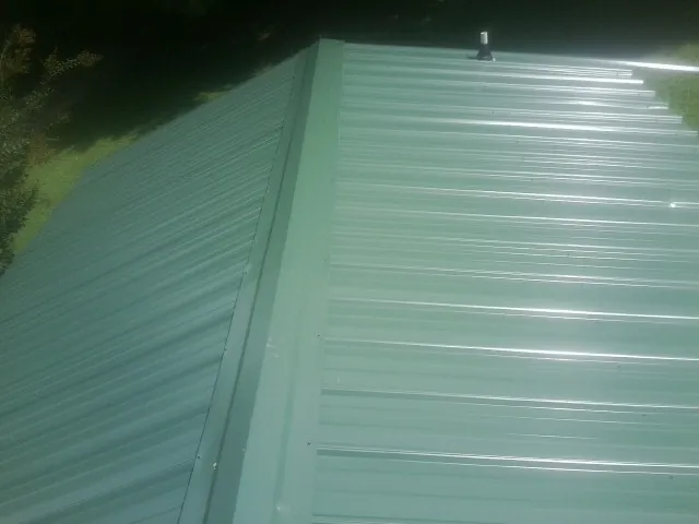 New green metal panels meeting at the ridge of a roof — Flat Roof Repair work by our crew in Clarkton
