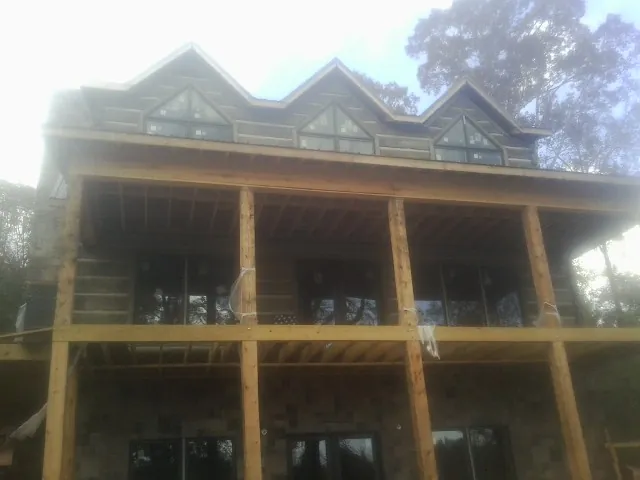 Dormers and porch framing on a large log home under construction — Roof Coating work by our crew in Clarkton