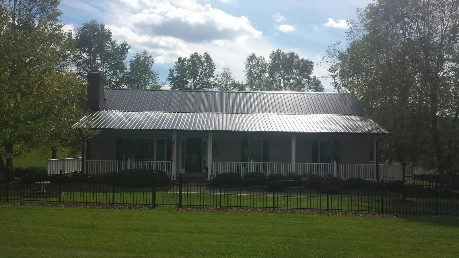 Gray metal roof on a brick ranch with a full width front porch — Gutter Guard Installation work by our crew in Clarkton