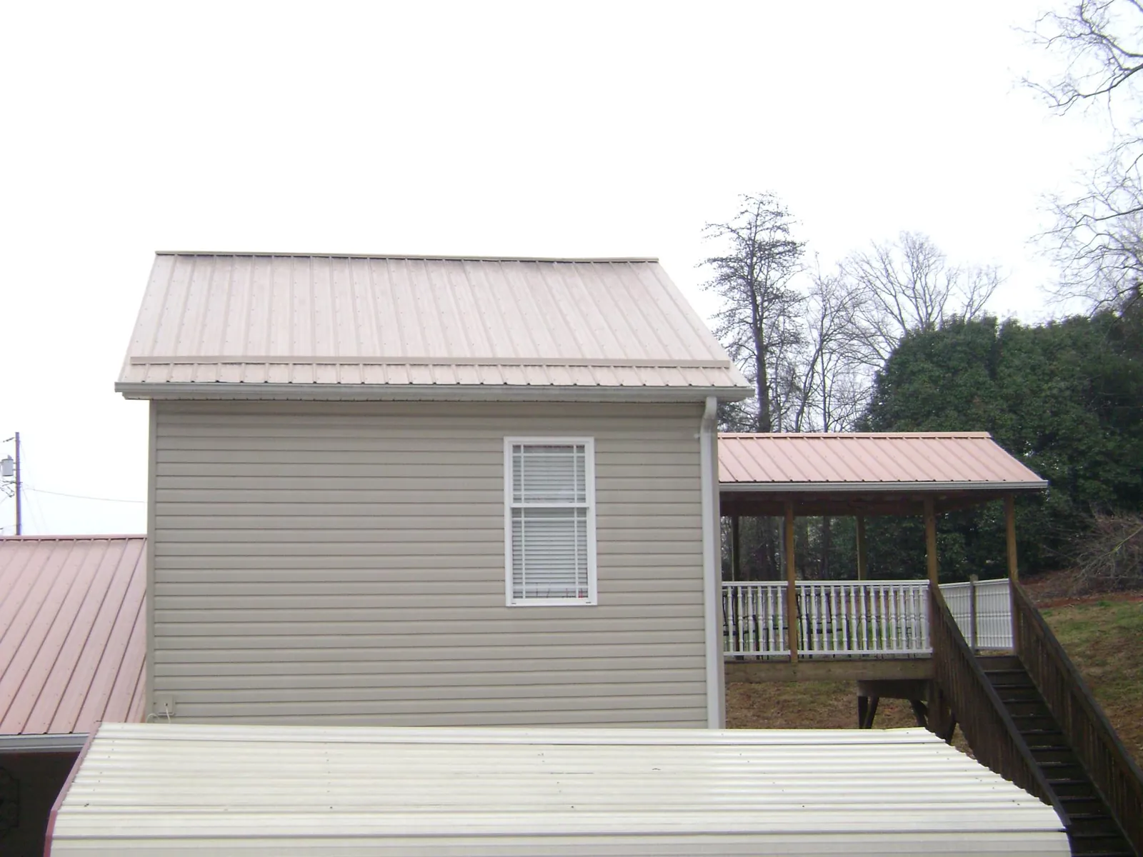 Tan metal roofs on a two story addition and attached porch, from a Roof Replacement job in Clarkton