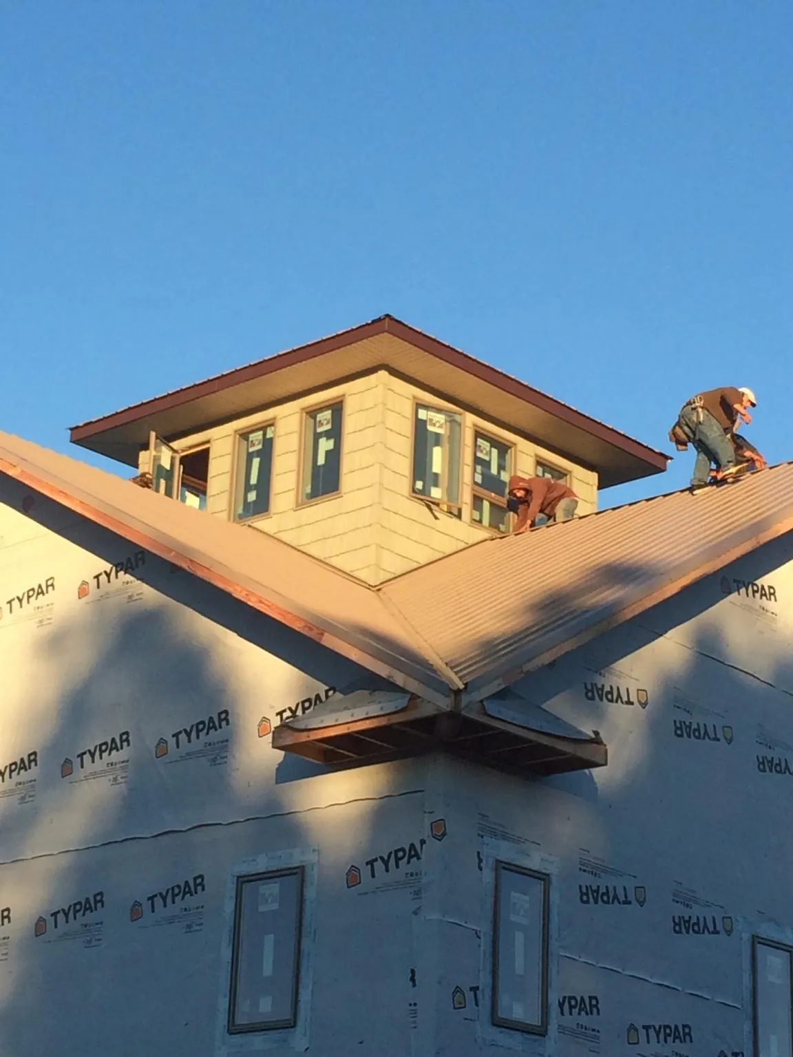 Roofers working around a rooftop cupola on a new metal roof at sunset — Roof Waterproofing in Clarkton by Roofing Brothers